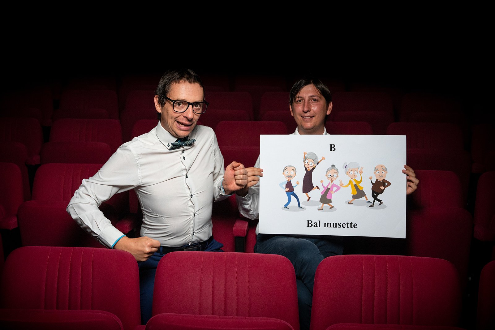 Deux comédiens présentent une illustration humoristique pendant le spectacle Hautes Définitions dans une salle de théâtre.
