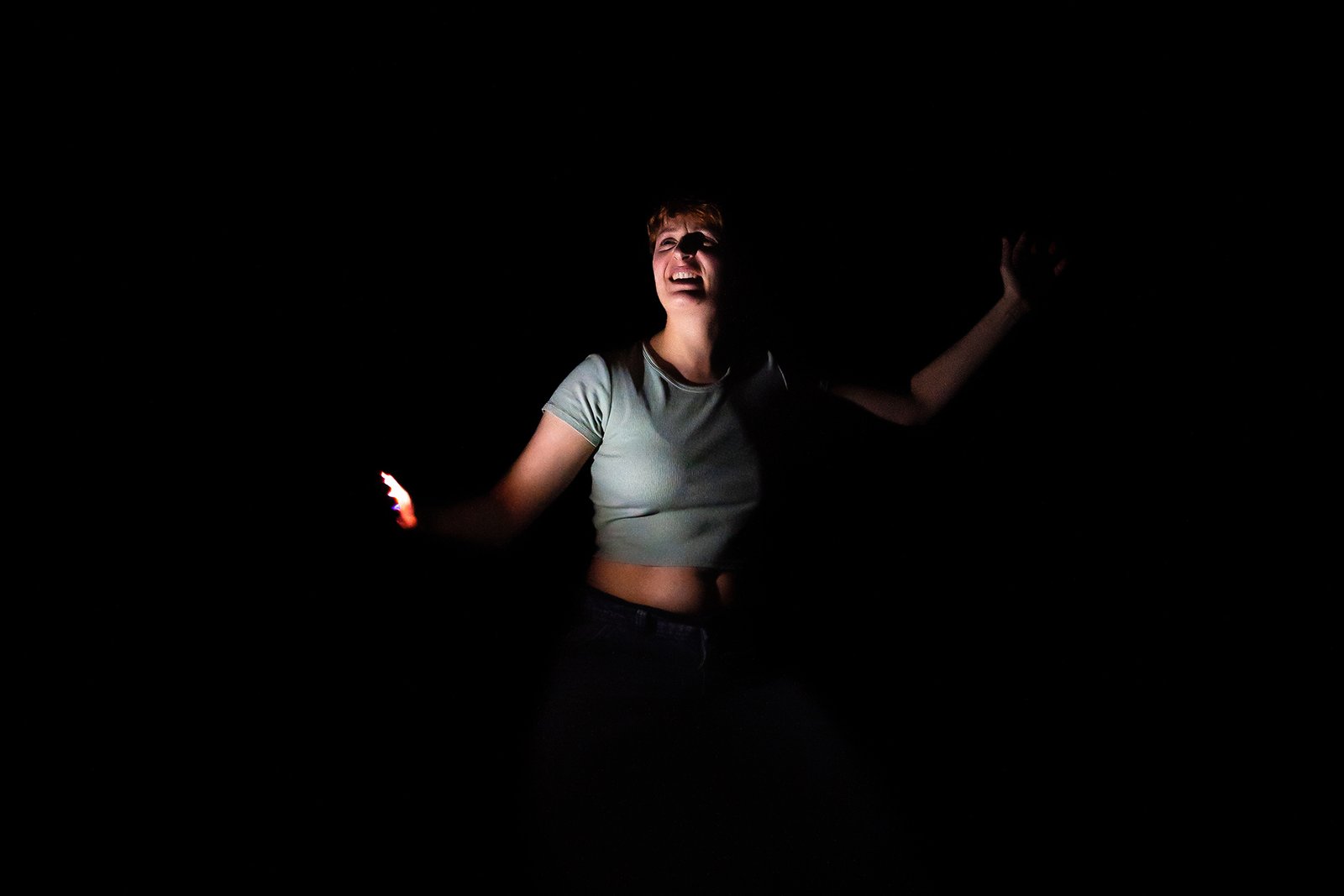 Comédienne seule sur scène éclairée dans l’obscurité lors du spectacle de théâtre Mal à Dire.