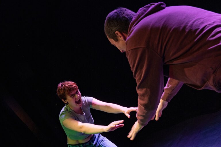 Deux comédiens interagissent sur scène dans une scène intense du spectacle Mal à Dire.