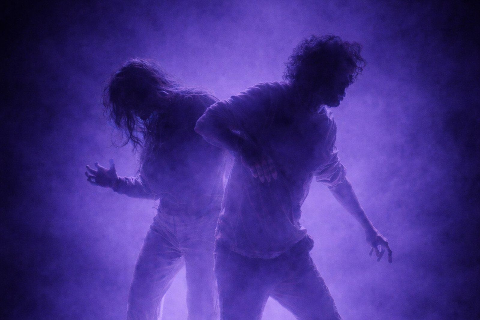 Deux silhouettes de comédiens évoluent dans la brume violette sur scène pendant le spectacle Mal à Dire.